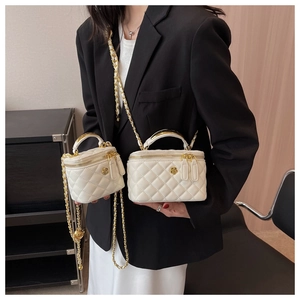 Close-up of quilted white leather mini buckets with golden camellia buckles and chain straps