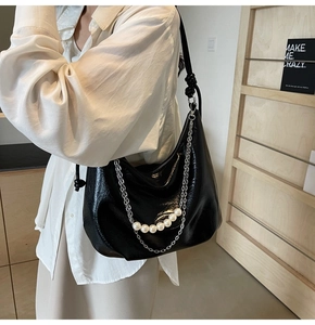 Dettaglio borsa hobo nera a mezzaluna con catena argentata e perle bianche decorative