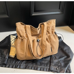 Macro detail of khaki pleated tote bag with drawstring side pocket on leather backdrop