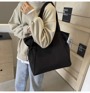 Detailed view of large black canvas tote bag with functional side drawstrings for styling
