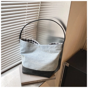 Detail of denim tote bag with leather bottom and black-and-white checkered lining