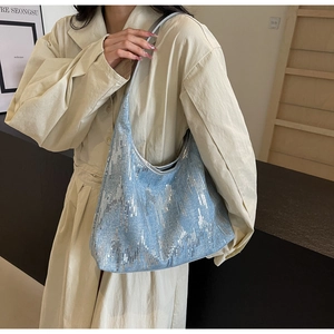 Detail of light blue hobo bag with silver sequins on a model wearing a trench coat