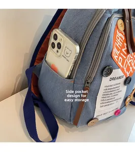 Detail of denim backpack side pocket showing convenient smartphone storage and patches