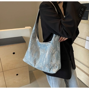 Detail of light blue sequin hobo bag with silver metallic shoulder strap on model