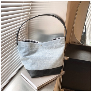 Detail of denim shoulder bag with leather bottom and silver clasp closure mechanism