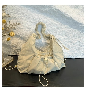 Close-up of pleated beige canvas tote with drawstring detail and ruffled shoulder strap