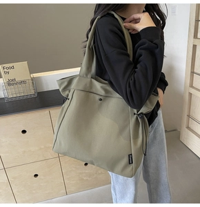 Detail view of khaki canvas tote bag featuring side drawstrings and magnetic closure snap
