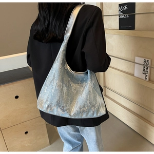 Detail of blue sequin hobo bag with silver strap showing texture and size on model