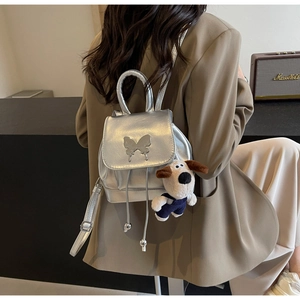 Détail du sac à dos argenté métallisé avec boucle papillon et breloque chiot mignonne