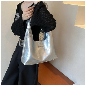 Model wearing a metallic silver chain shoulder bag with heart buckle and pleated texture