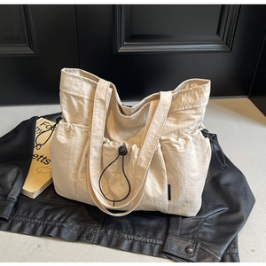 Detailed close-up of cream pleated tote bag featuring drawstring pockets and nylon texture