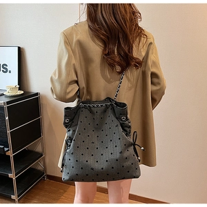Detail view of large grey polka dot tote bag with chain strap and bow accents