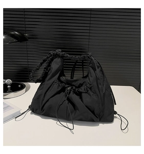 Close-up of black pleated nylon tote bag with drawstring texture and wavy handles