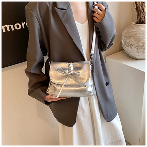 Macro detail of silver metallic PU crossbody bag featuring elegant pleated bow and chain
