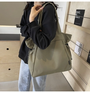 Detail of olive green canvas tote bag with functional side drawstrings and wide shoulder strap
