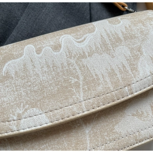 Detailed close-up of patterned beige crossbody bag showing premium stitching and mountain prints