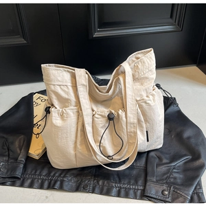 Detailed view of beige canvas tote bag with drawstring pockets and pleated fabric texture