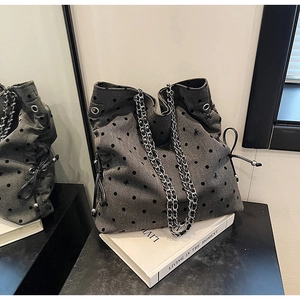 Detail of grey polka dot tote with bow embroidery, chain strap, and drawstring side accents