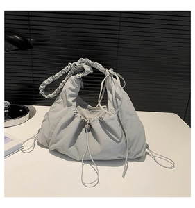Macro view of light grey pleated canvas hobo bag with ruffle texture and drawstring detail