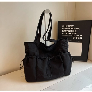 Detail of black large capacity canvas tote bag with functional drawstring pockets