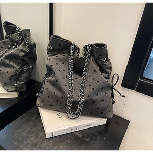 Detail of grey polka dot tote bag with metal chains and decorative side drawstrings