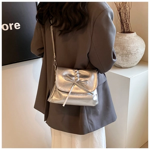 Detailed view of silver metallic pleated crossbody bag with decorative bow and sleek strap