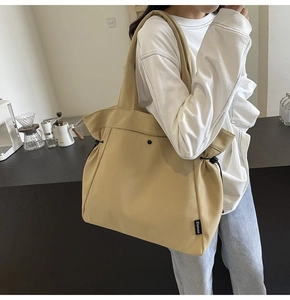 Detail of canvas tote bag showing drawstring side and woven brand label on shoulder strap