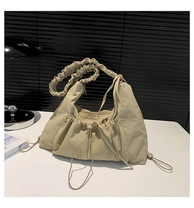Detail of pleated beige canvas tote bag with adjustable drawstring and soft cloud strap