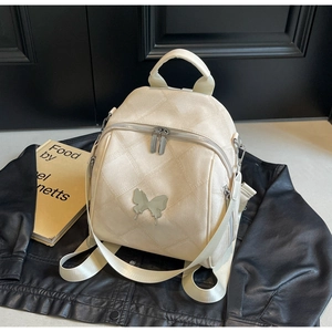 Detail of off-white quilted backpack with silver butterfly logo on a leather jacket