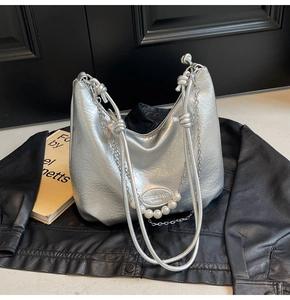 Dettaglio della borsa hobo argento metallizzato con nappe di perle e catene sottili