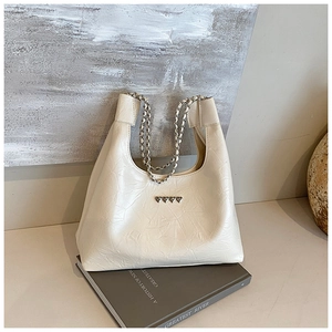 Detail of cream PU tote bag with pleated texture, gold chain strap, and heart buckles
