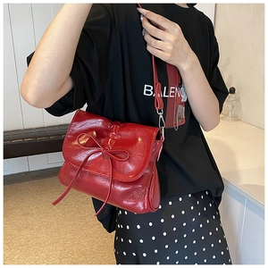Detail of red glossy pleated shoulder bag with bow and adjustable silver hardware hook