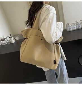 Detail of khaki canvas tote bag featuring side drawstring cords and thick woven texture