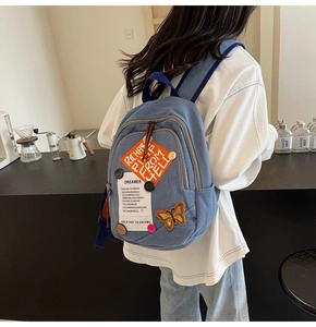 Detail of blue denim backpack featuring butterfly patches and retro DIY embroidery accents