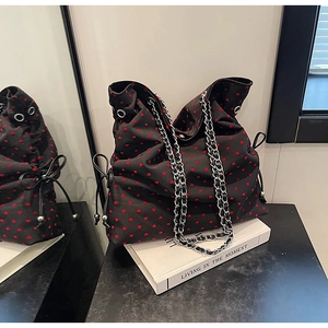 Detail of black canvas tote bag with red heart pattern and silver metal chain strap