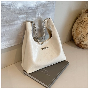 Detail of cream pleated faux leather tote bag featuring heart rivets and chain strap