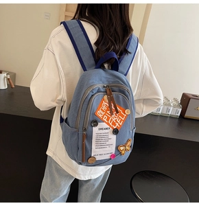 Detail view of denim backpack showing colorful patches and butterfly embroidery