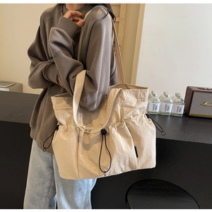 Detail of beige large capacity tote bag with drawstring pockets and wide shoulder strap