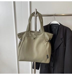Macro detail of olive green tote bag with drawstring folds and minimalist black buckle