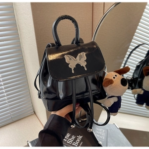Détail du mini sac à dos en cuir verni noir avec papillon argenté et breloque chien