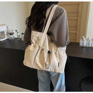 Detailed side view of off-white canvas tote bag with functional drawstring pockets