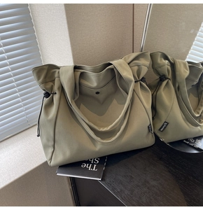 Detail of army green canvas tote with dual handles, side drawstrings and magnetic closure