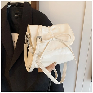 Detail of cream pleated crossbody bucket bag with elegant ribbon bow and silver hardware