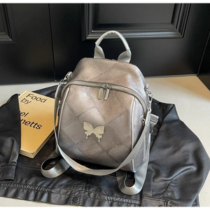 Detail of silver metallic quilted backpack with butterfly buckle and top handle
