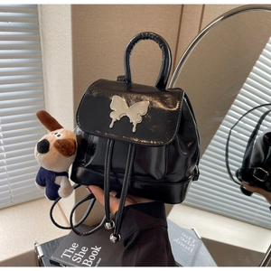 Détail du mini sac à dos en cuir verni noir avec papillon argenté et breloque chien