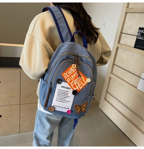 Detail view of denim backpack with vintage patches, butterfly embroidery and dreamer tag