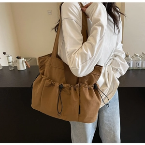 Detailed view of caramel pleated tote bag with three drawstring pockets and wide strap