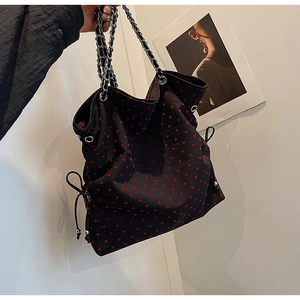 Close-up of black canvas tote bag with red heart pattern and chain shoulder strap