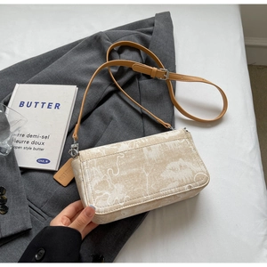 Detail of printed fabric handbag with leather strap on a stylish grey blazer background