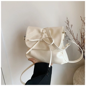 Detail of off-white pleated crossbody bucket bag with bow and polished finish